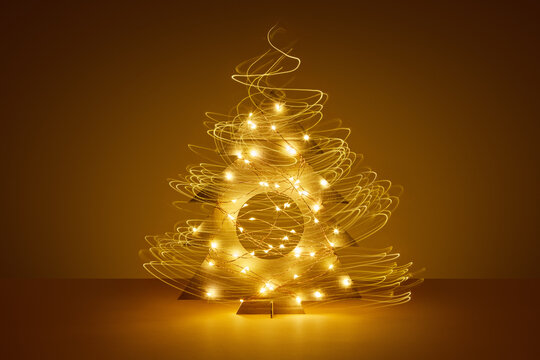 Long exposure of glowing garlands decorating cardboard Christmas tree