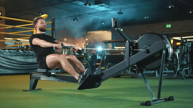 A committed man with a beard is engaged in a vigorous full-body workout using a rowing machine in a gym with vibrant and dynamic lighting, showcasing his dedication to fitness. Camera 8K RAW. 