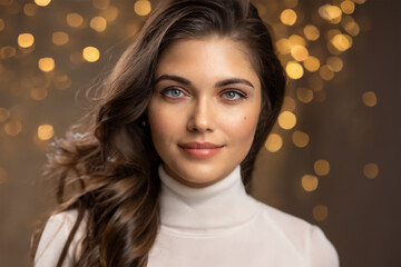 Portrait of a beautiful woman model, brunette with long hair and gray eyes in a white turtleneck.