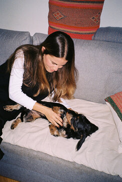 Analog image of a woman lovingly stroking the belly of her puppy
