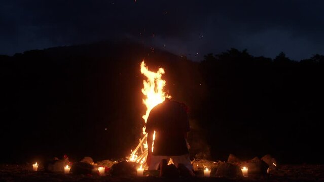 A Shaman Ceremony and Kneeling before a Bonfire