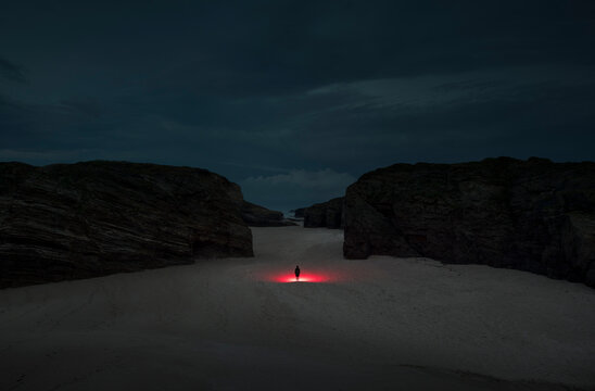 Surreal standing person on dreamlike beach at night