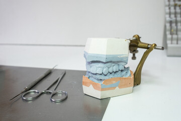 a denture model on a laboratory table with some working utensils. It is the upper and lower jaw. © LaMorenita