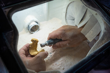 A dental technician prepares to polish the details of a dental stone model with the handpiece to make it ready to work on. © LaMorenita