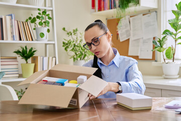 Female consumer sitting at home unpacking cardboard box with online purchases
