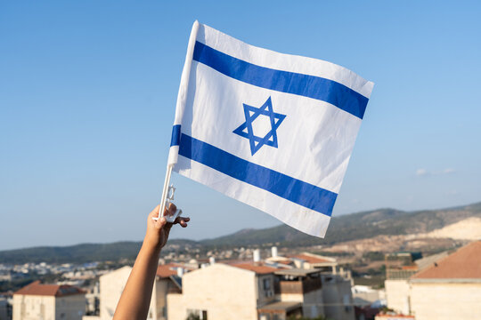 Child's Hand with Israeli Flag on Israel View Background.