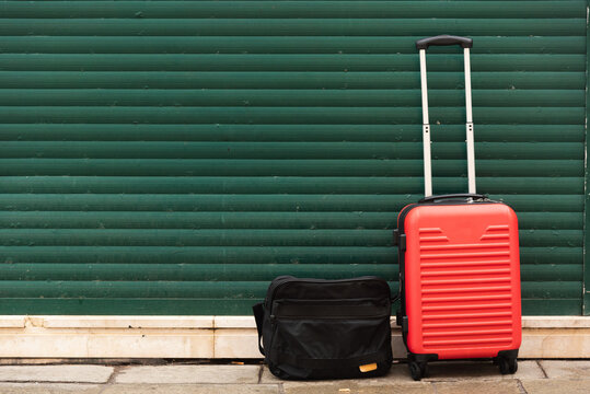 Red baggage with briefcase in front of green iron gate in Venice