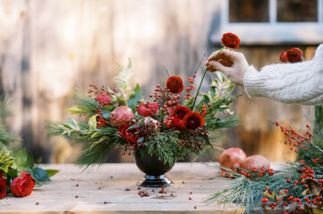 florist in white knit sweater making christmas floral centerpiece