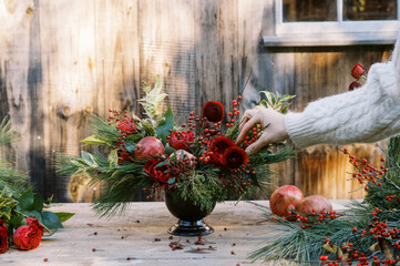 florist in white knit sweater making christmas floral centerpiece