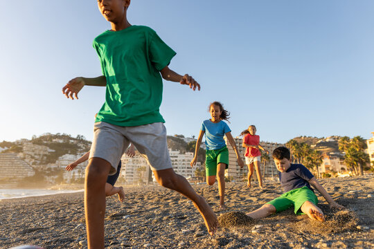 Fototapeta children's soccer game on a beach at sunset