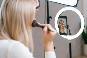 Rear view young woman making beauty and cosmetic tutorial video content for social media. Beauty...