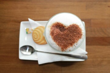 cup of coffee heart-shaped ,cookies and a spoon in a white plate - obrazy, fototapety, plakaty
