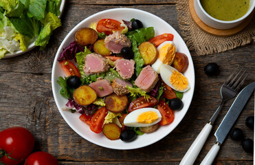 Fresh and healthy salad with vegetables and fried tuna on a wooden background.