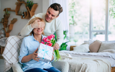 Close up image of young smiling man while he making surprise for his mature mother with some holiday in domestic room. Mothers day, birthday or womens day concept - 771004176