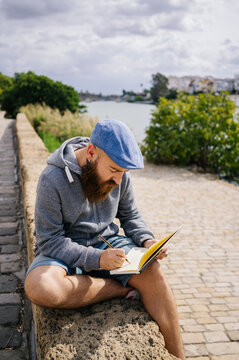 Concentrated illustrator drawing in planner near river