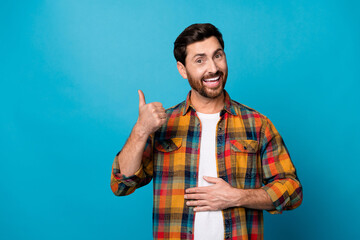 Photo portrait of nice young guy touch stomach good digestion show thumb up wear trendy plaid garment isolated on blue color background