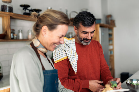 couple laughing while cooking together in kitchen