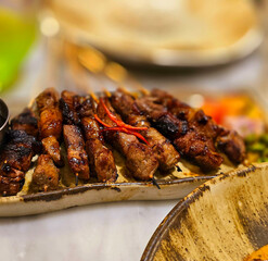 Homemade beef Satay marinated with spice and sweet soy sauce, coriander beef satay, served on plate with onion, chilli, soy sauce and tomato