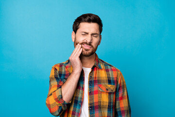 Photo portrait of nice young guy touch cheek suffer toothache dressed stylish checkered garment isolated on blue color background