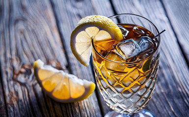 Iced tea with lemon and ice on a wooden background - obrazy, fototapety, plakaty