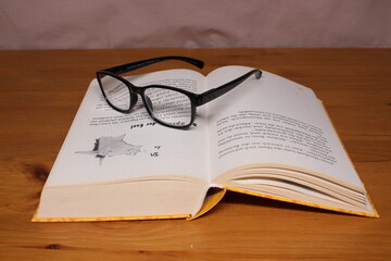 An image of an open book and glasses lying on it.
