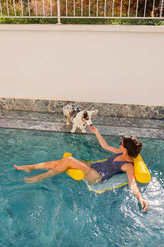 Woman spending time with her dog in the pool 