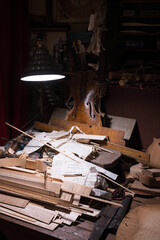Detail of the messy work table of the master craftsman luthier maker of high-end violins. pieces of...