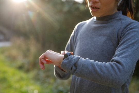 Sportswoman analyzing jogging track on smartwatch in sunlight