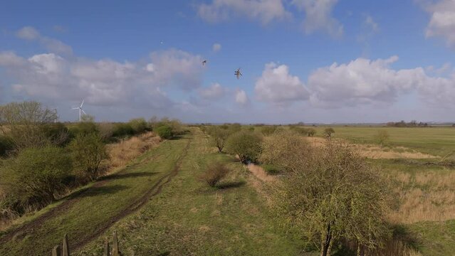 Drone shot of the grassy fields around Frodsham Wind Farm on a sunny day in Frodsham, England, UK