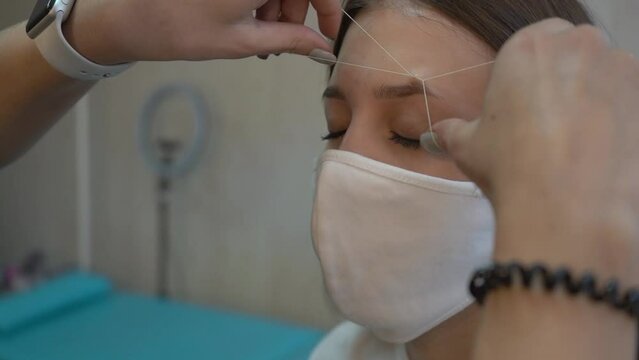 Beautician plucks eyebrows using thread