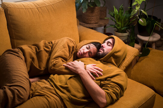 Surreal portrait of sleeping couple merged with sofa