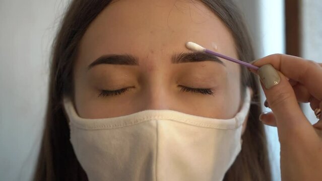 Beautician applies recovery oil after eyebrow shaping