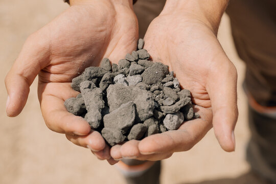 A man holds a pile of ore with gold particles