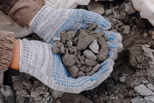 A man holds a pile of ore with gold particles - Powered by Adobe