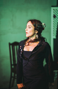 Stylish woman in black dress standing against wall