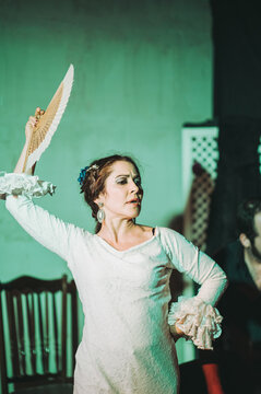 Female flamenco artist with hand fan dancing in studio