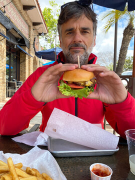 Man Wearing a red jacket Eating A Burger