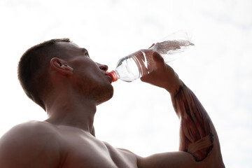 A close-up shot of a muscular man drinking water from a bottle. The image captures the essence of...