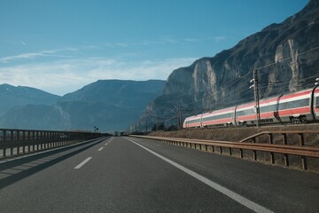 Train goes along the highway in the mountains
