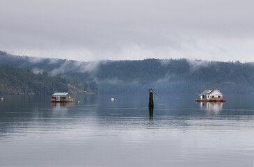 Floating cabins in front of the shore of Cowichan Bay during a winter season on Vancouver Island in British Columbia, Canada