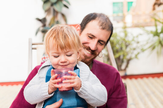 Happy baby holding milk glass sitting on dad