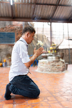 Thai man praying in Buddhist temple.