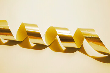 Golden and shiny party ribbon on a golden background