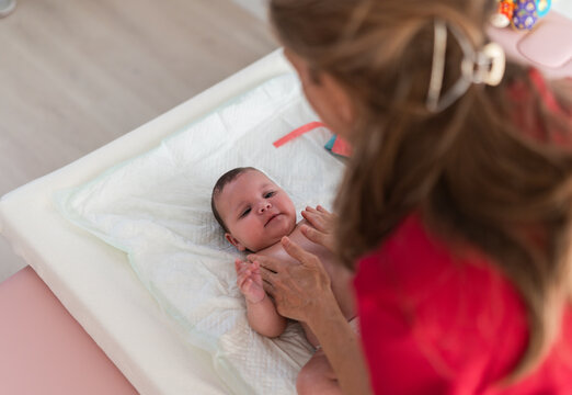 Mother changing diaper on her newborn baby in a changing room