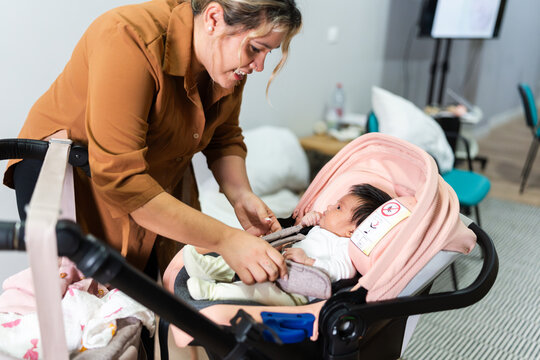Portrait of mother helping her newborn baby in stroller