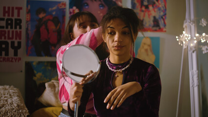 Two multicultural girls have fun and spend leisure time together. Asian girl combs African American teenager hair, makes hairstyle. Comfortable home with cozy stylish interior. Friends relationship.