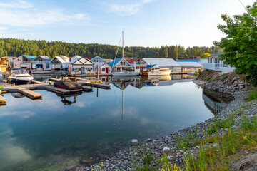 Small boathouses, boat slips, float homes and docks at a marina along the shore on Lake Pend...
