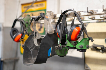 Welding helmets, protective glasses, ear protection hung in a row in a welding workshop