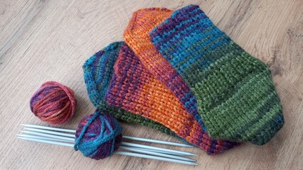 Colorful knitted socks. Needlework. Balls of woolen threads and knitting needles. Close-up.