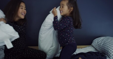 Pillow fight, girls and funny children in bedroom, family bond or kids having fun together in home. Siblings, playing game in bed with cushions and happy sisters laugh with freedom, energy or excited